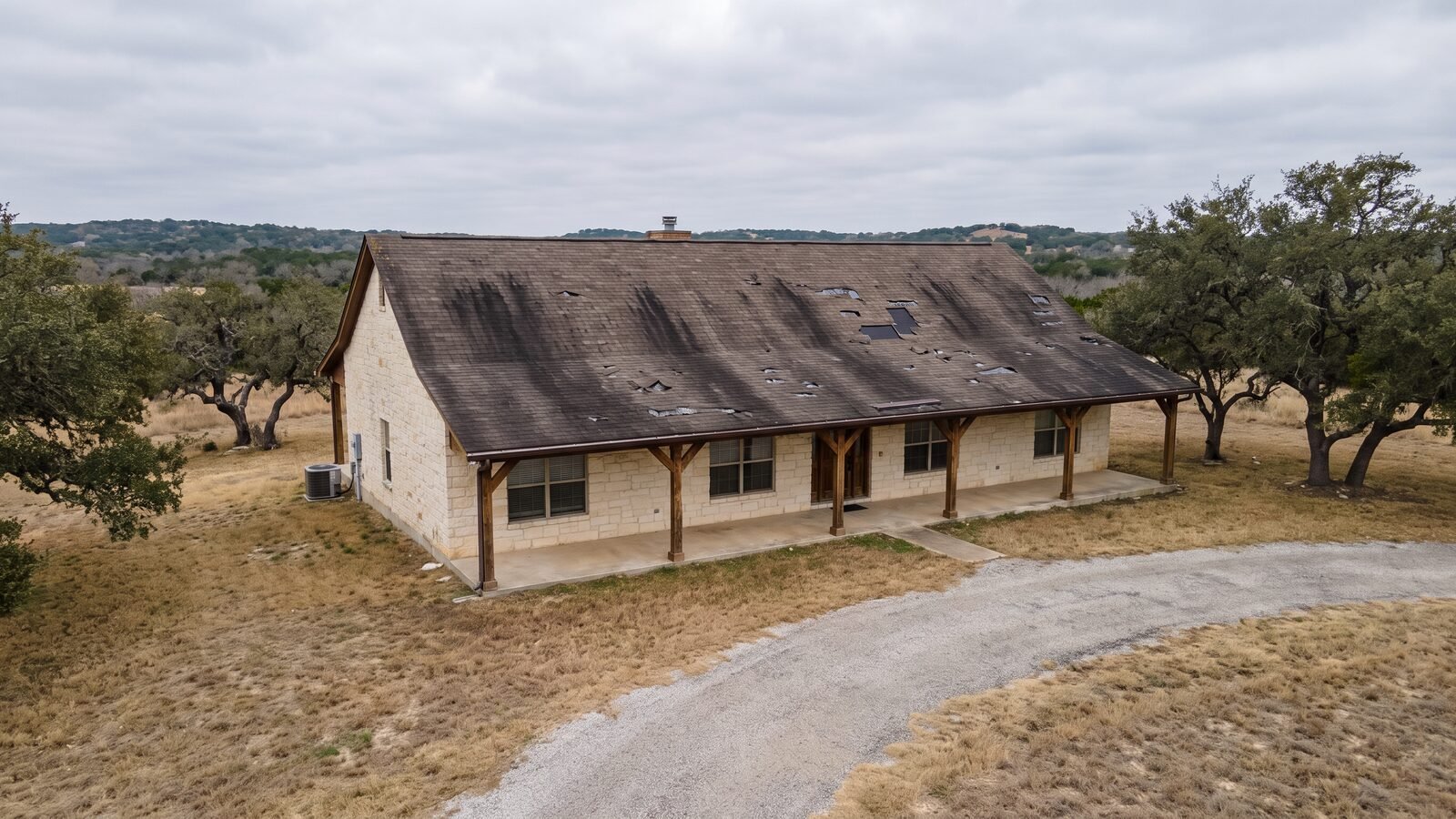 Hill Country limestone ranch house with badly aged, streaked and curling asphalt shingle roof
